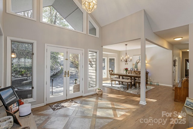 doorway with baseboards, wood finished floors, a notable chandelier, and french doors