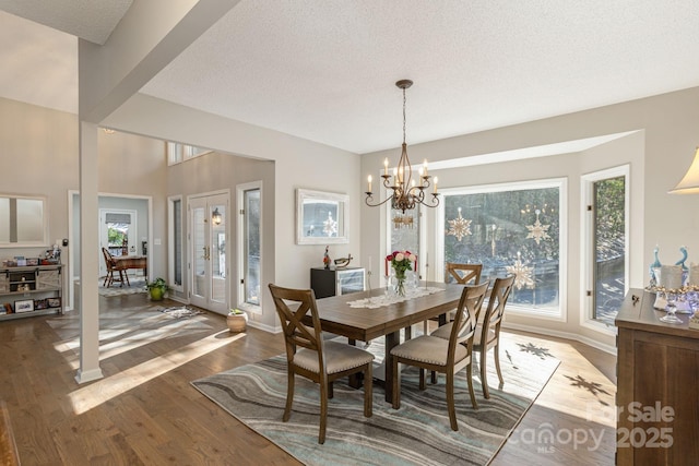 dining area featuring a notable chandelier, a textured ceiling, a wealth of natural light, and wood finished floors