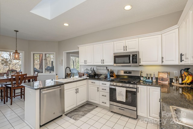 kitchen featuring recessed lighting, stainless steel appliances, a peninsula, a sink, and white cabinets