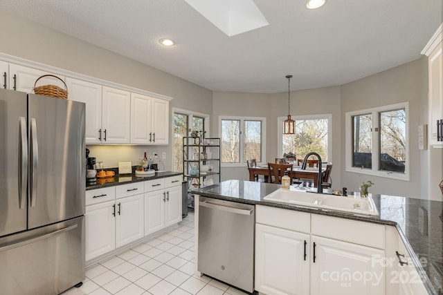 kitchen with light tile patterned floors, stainless steel appliances, a sink, white cabinets, and pendant lighting