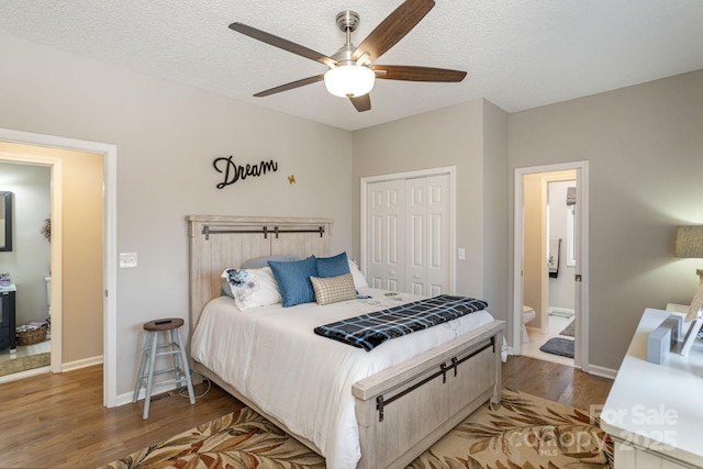 bedroom featuring a closet, a ceiling fan, a textured ceiling, ensuite bath, and wood finished floors