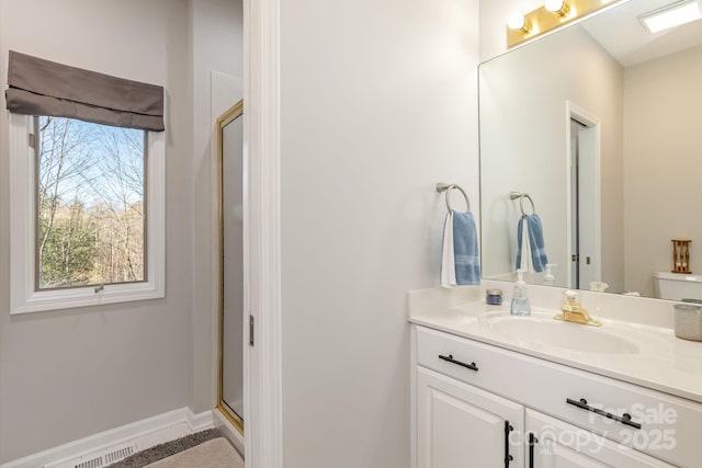 full bath with toilet, visible vents, vanity, baseboards, and a stall shower