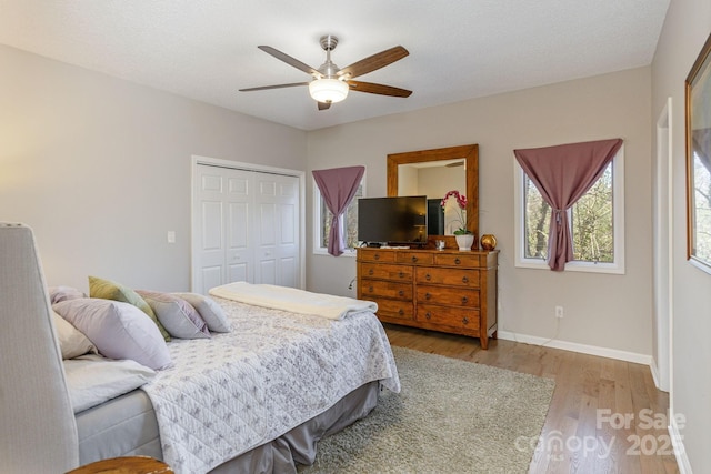 bedroom with a closet, wood finished floors, a ceiling fan, and baseboards