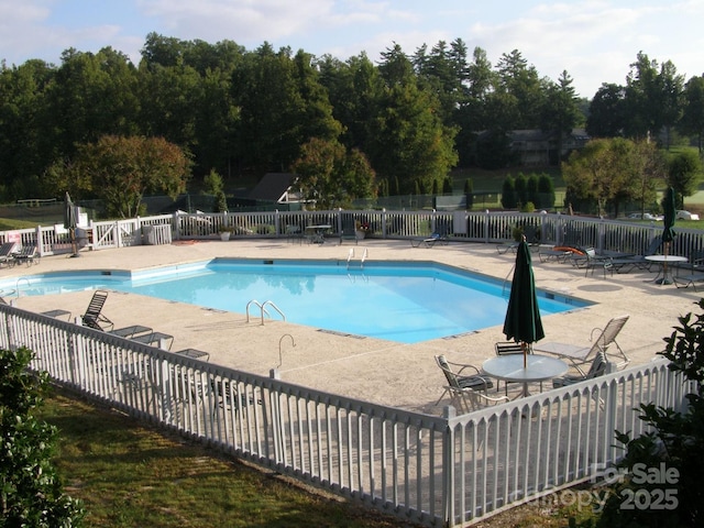 community pool with a patio and fence