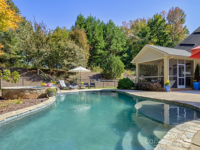 view of swimming pool featuring a fenced in pool, a patio area, a sunroom, and a fenced backyard