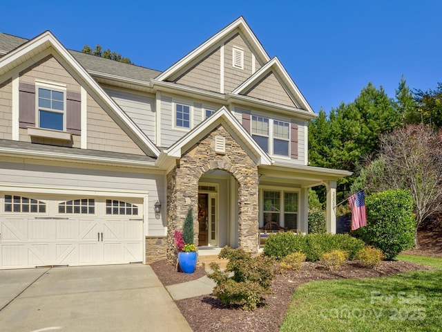 craftsman-style home with a garage, stone siding, and concrete driveway