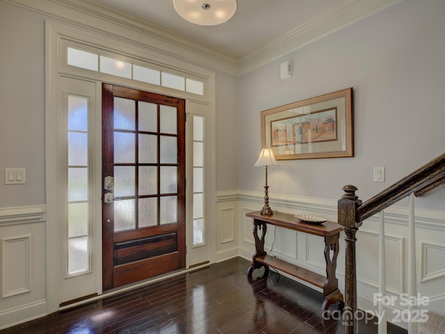 entrance foyer with crown molding, a decorative wall, stairway, dark wood-type flooring, and wainscoting