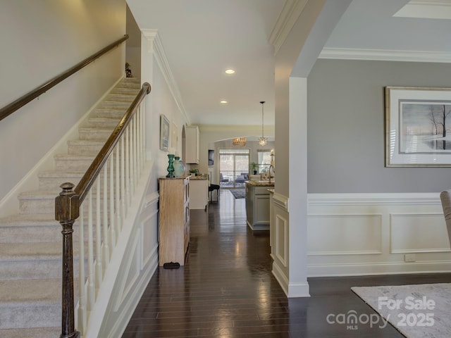 interior space with dark wood-style floors, ornamental molding, a wainscoted wall, and a decorative wall