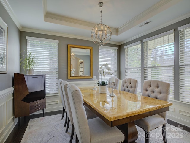 dining area featuring a raised ceiling, visible vents, a notable chandelier, and wood finished floors