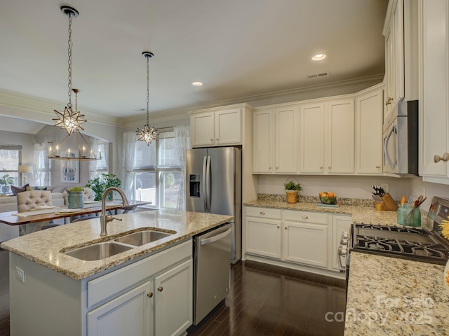 kitchen featuring dark wood finished floors, stainless steel appliances, open floor plan, a sink, and an island with sink