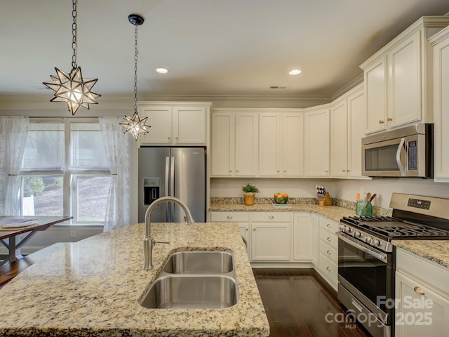 kitchen featuring white cabinets, appliances with stainless steel finishes, dark wood-style flooring, pendant lighting, and a sink