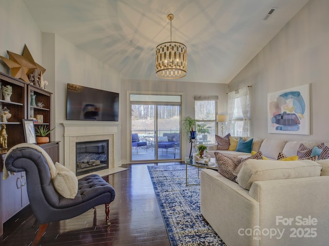 living room with visible vents, a premium fireplace, wood finished floors, an inviting chandelier, and high vaulted ceiling