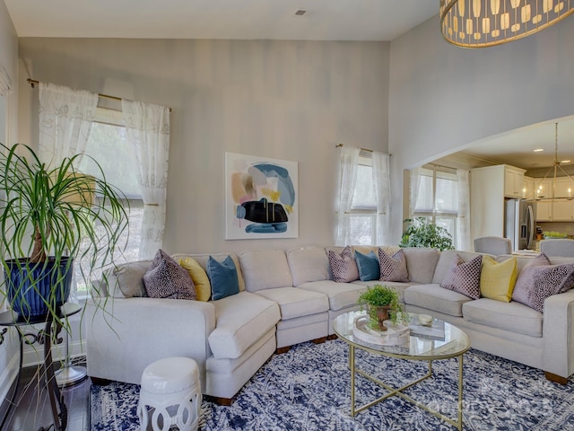 living room featuring high vaulted ceiling, wood finished floors, and an inviting chandelier