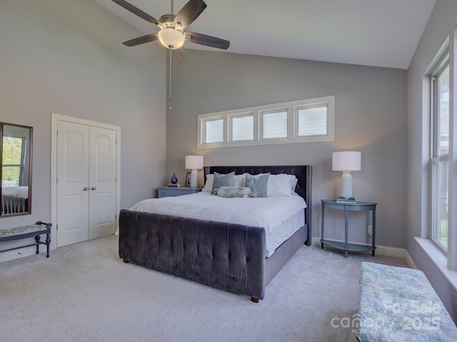 carpeted bedroom with ceiling fan, high vaulted ceiling, a closet, and baseboards