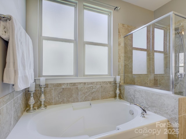 bathroom with a wealth of natural light, a garden tub, and tiled shower