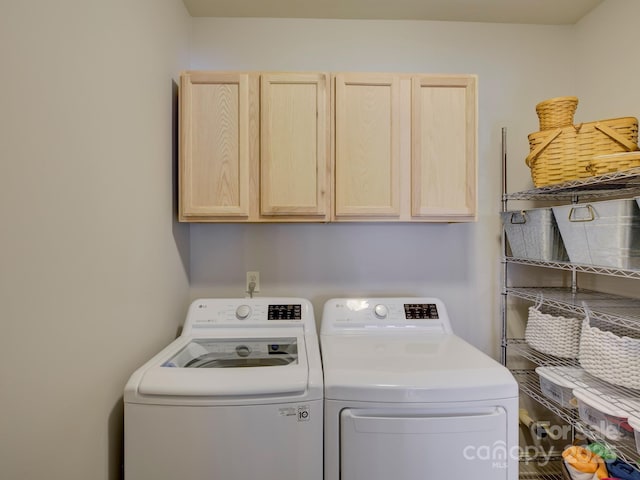 clothes washing area featuring washing machine and dryer and cabinet space