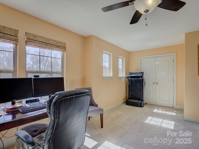 carpeted office space featuring a ceiling fan and baseboards