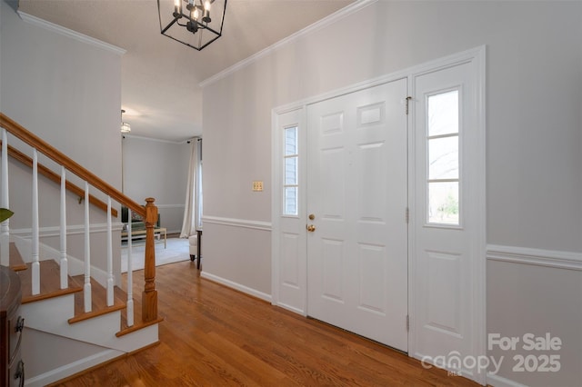 entryway with a wealth of natural light, stairway, ornamental molding, and wood finished floors