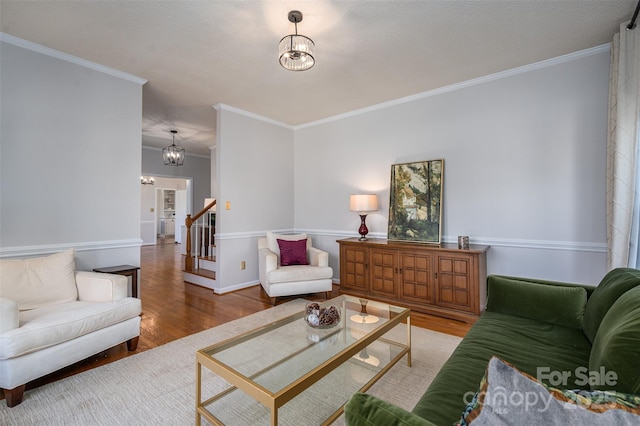 living room with light wood-type flooring, a notable chandelier, crown molding, and stairway