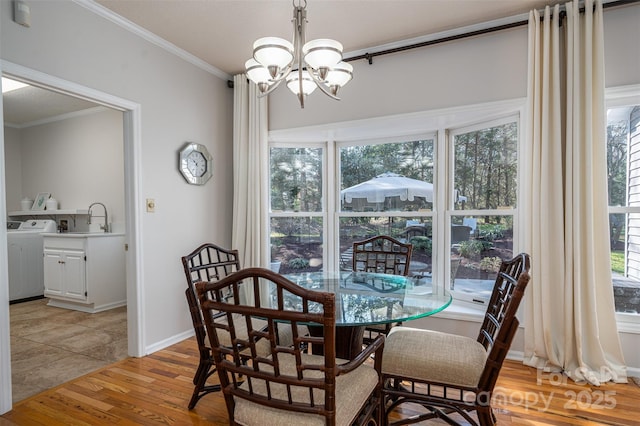 dining area featuring baseboards, an inviting chandelier, washer / dryer, light wood-style floors, and crown molding