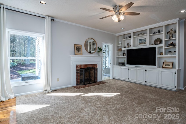 unfurnished living room with a ceiling fan, baseboards, a fireplace, a textured ceiling, and crown molding