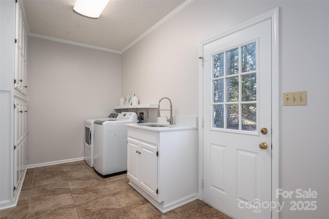 washroom with crown molding, baseboards, washer and clothes dryer, cabinet space, and a sink