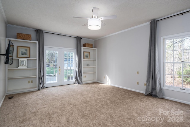 carpeted empty room with visible vents, baseboards, french doors, a textured ceiling, and crown molding