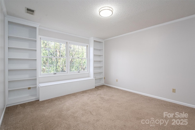 empty room with visible vents, a textured ceiling, crown molding, and carpet