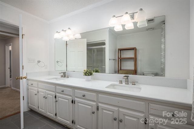 full bathroom with tile patterned flooring, crown molding, a stall shower, and a sink