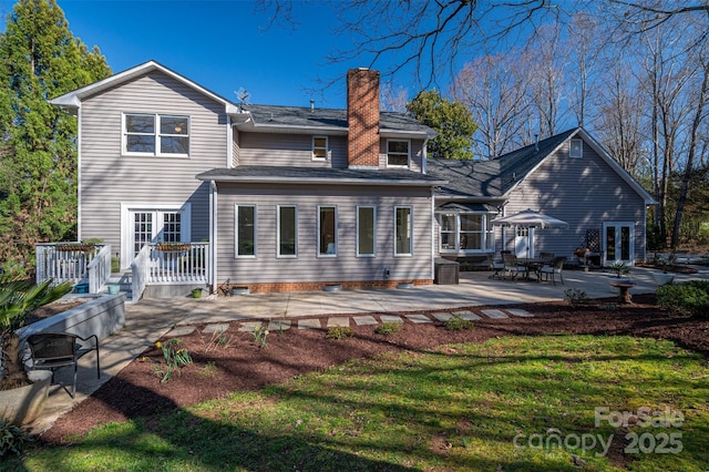 rear view of property with a patio, a wooden deck, french doors, and a chimney