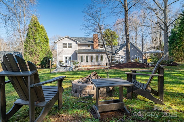 back of house featuring a chimney, a fire pit, and a yard