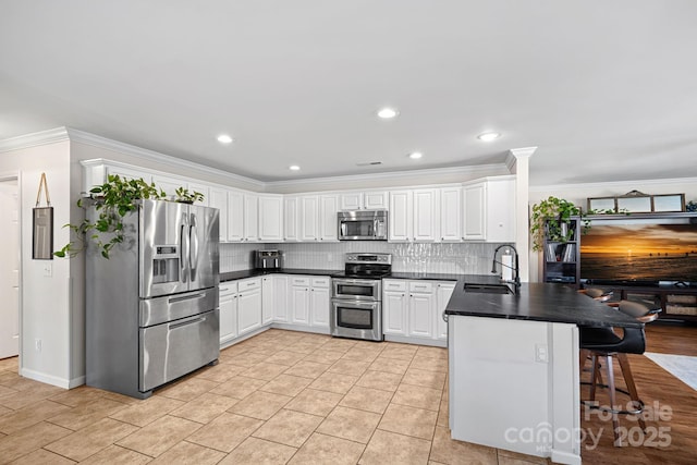 kitchen featuring a peninsula, a sink, white cabinetry, appliances with stainless steel finishes, and tasteful backsplash