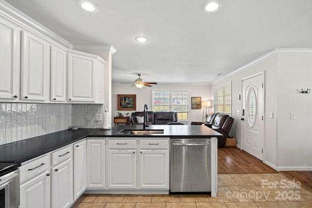 kitchen with dark countertops, open floor plan, stainless steel appliances, white cabinetry, and a sink