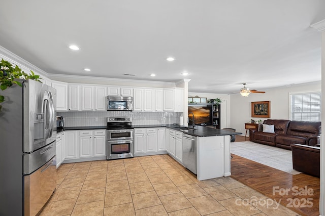 kitchen featuring open floor plan, stainless steel appliances, light tile patterned floors, and a peninsula