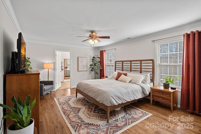 bedroom with a ceiling fan, crown molding, light wood-style flooring, and ensuite bathroom