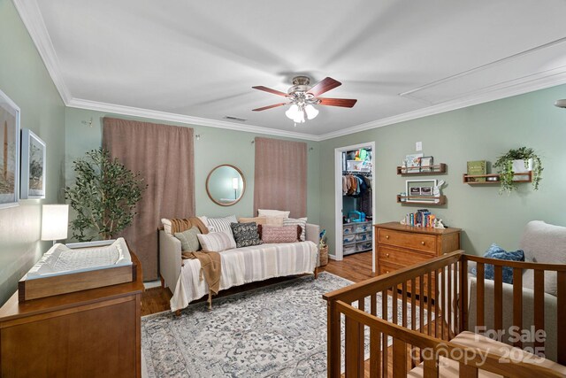 bedroom featuring a closet, wood finished floors, attic access, and crown molding