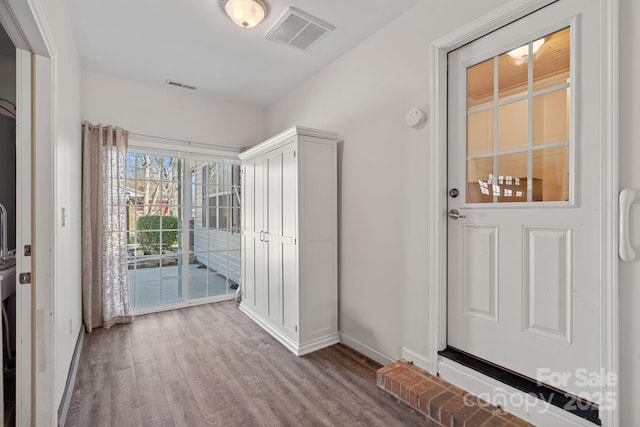 doorway featuring visible vents, baseboards, and wood finished floors