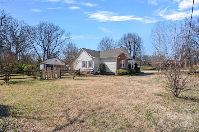 view of home's exterior with fence, a lawn, and an outdoor structure