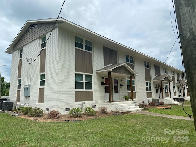 view of front of home with brick siding, crawl space, a front yard, and central air condition unit