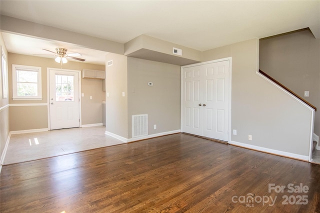 foyer entrance featuring a ceiling fan, visible vents, baseboards, and wood finished floors