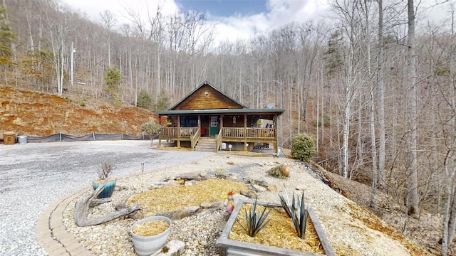 view of front of home featuring covered porch and a view of trees