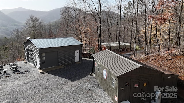 exterior space with a mountain view, a view of trees, and an outdoor structure