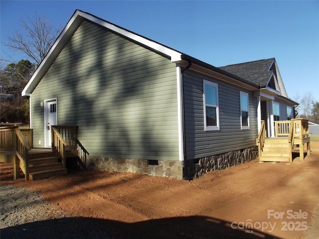 view of side of property featuring crawl space and a deck