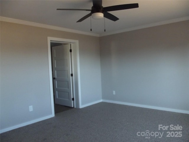 unfurnished room featuring baseboards, dark carpet, ceiling fan, and crown molding