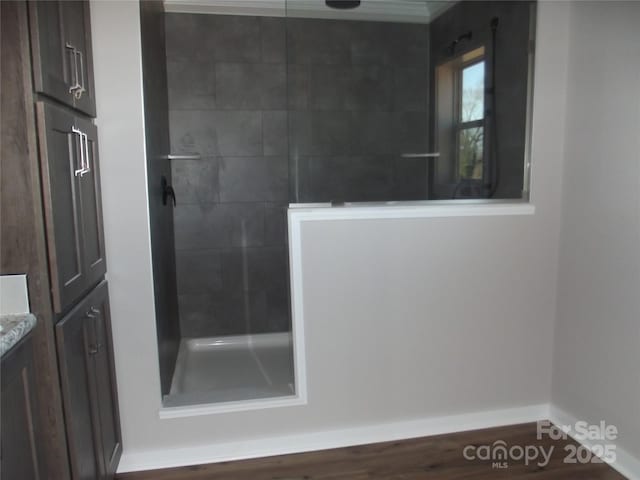 bathroom featuring a walk in shower, vanity, and baseboards