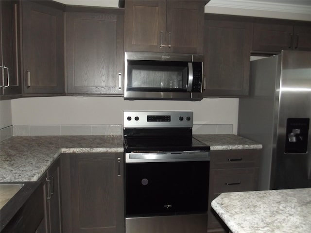 kitchen with stainless steel appliances, dark brown cabinets, and crown molding