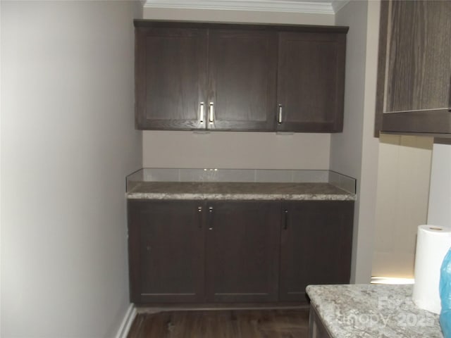 kitchen featuring dark wood-style floors, dark brown cabinets, ornamental molding, and baseboards