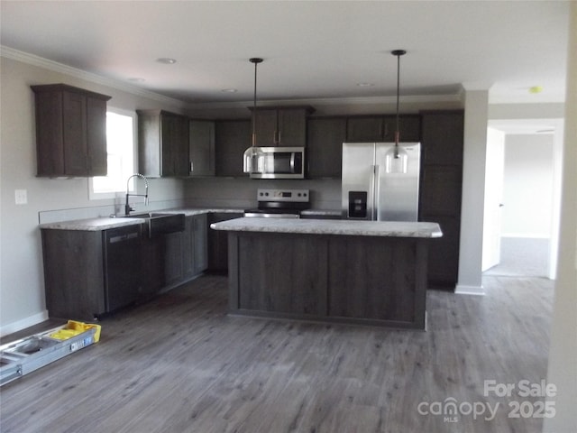 kitchen featuring a kitchen island, wood finished floors, stainless steel appliances, crown molding, and a sink