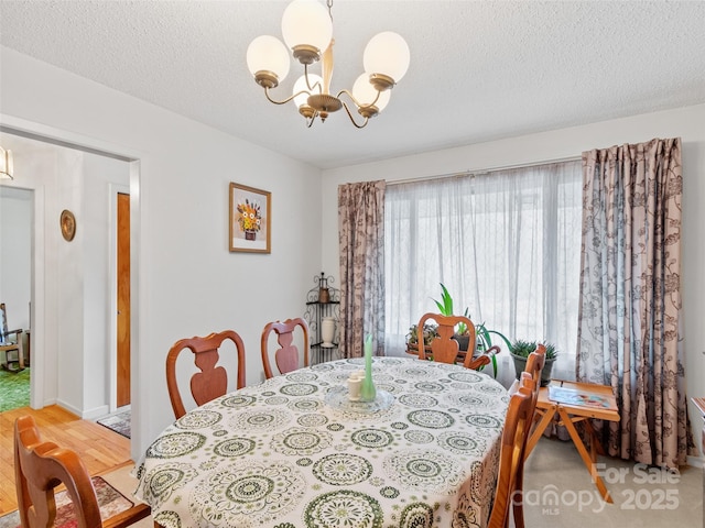 dining space featuring a notable chandelier, wood finished floors, and a textured ceiling