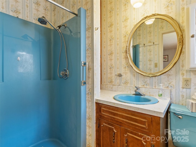 bathroom featuring wallpapered walls, toilet, vanity, and walk in shower